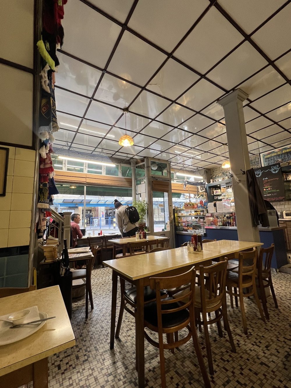 Plain cafe interior looking towards the front window, with wooden tables, bentwood chairs and a tiled floor