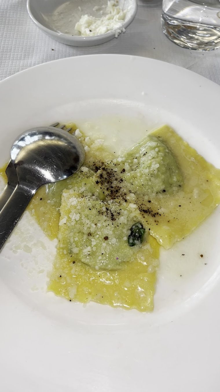 A plate of green filled pasta with butter and cracked pepper