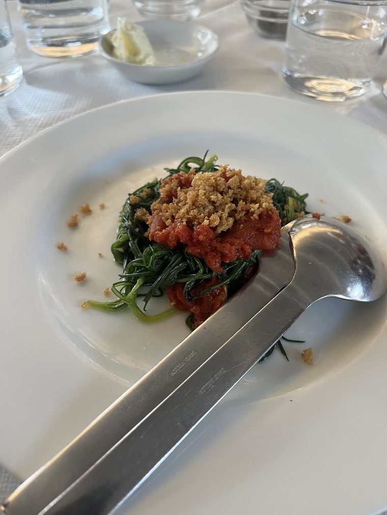 A starter of greens and tomato topped with breadcrumbs, shot from above